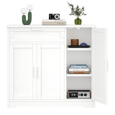 a white cabinet with books and plants on it's shelves next to a camera