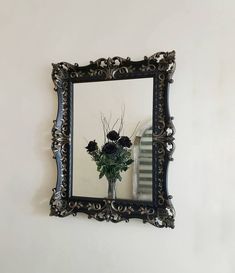 there is a vase with flowers in the mirror on the wall next to the stairs