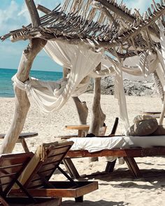 a bed sitting under a wooden structure on top of a beach