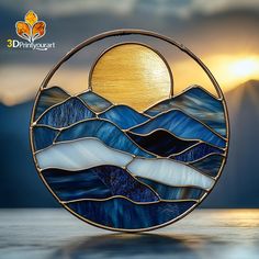 a stained glass sun catcher sitting on top of a wooden table in front of mountains