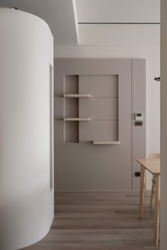 an empty room with a table and shelves in the corner, next to a white wall