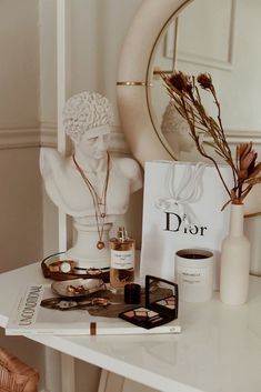 a white table topped with lots of items and a vase filled with flowers next to a mirror