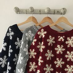 three sweaters hanging on a coat rack