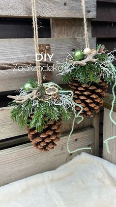 two pine cones are hanging from the side of a wooden fence with evergreen needles and other greenery