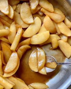 apples are being spooned into a sauce in a bowl