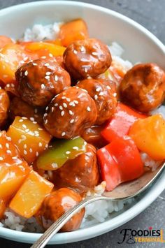 a white bowl filled with meatballs and veggies on top of rice next to a spoon