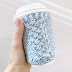 a hand is holding a cup cozying it's sleeve