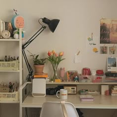 a white desk topped with a laptop computer next to a lamp and flower pot on top of it