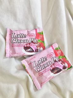 two pink chocolate bars sitting on top of a white sheet covered bed next to each other