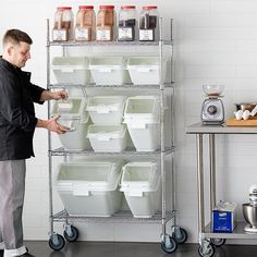 a man standing in front of a shelf filled with plastic containers and food on wheels