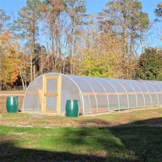 a large green house sitting on top of a lush green field in front of trees