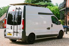 a white van parked in front of a brick building with a ladder on it's roof