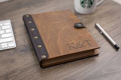 a wooden notebook sitting on top of a desk next to a keyboard and coffee cup