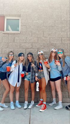 group of young women standing next to each other in front of a wall with sunglasses on