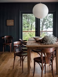 a dining room table and chairs in front of a window with a view of the woods