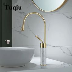 a bathroom sink with a gold faucet next to a white bowl and mirror