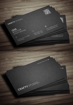 two black business cards sitting on top of a wooden table, with the words crafty studio