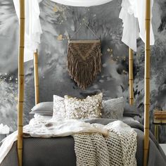 a bed with pillows and blankets on it in front of a wallpapered background