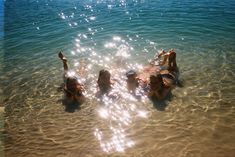 four people are floating in the water on their stomachs and arms with sun shining through them