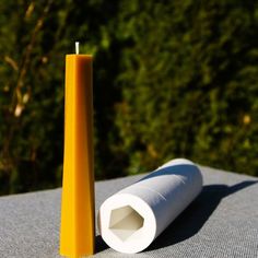 a yellow candle sitting on top of a table next to a roll of white paper