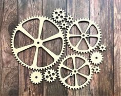 four gears are shown on a wooden surface, one is cut out and the other is made