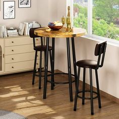 a small table with two stools next to it in front of a large window