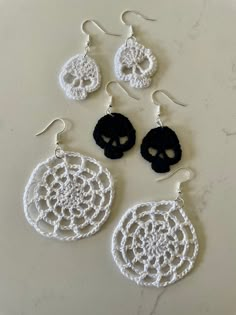 three crocheted earrings with black and white designs on them, one has a skull in the middle