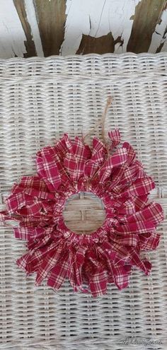 a white wicker chair with a red and white plaid flower on the back of it