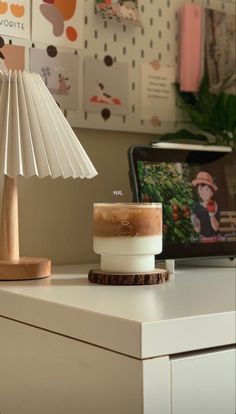 a white table with a lamp on top of it and a laptop computer in the background