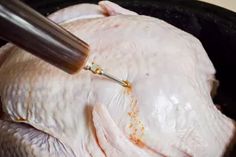 a chicken being cut into pieces with a meat thermometer in it's mouth