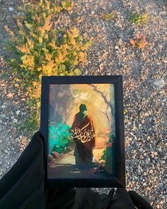 a person holding up a framed photograph with the words, jesus in arabic on it