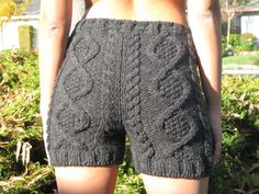 the back of a woman's shorts with an intricate design on it, in front of some bushes