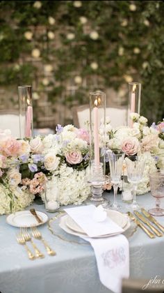 the table is set with flowers and candles for an elegant wedding reception in pastel tones