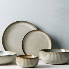 a set of four white dishes with gold rims on the bottom and one empty bowl in the middle