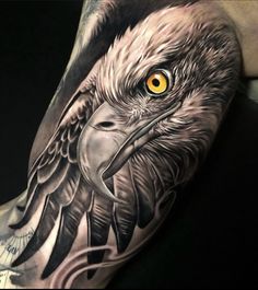 an eagle tattoo with yellow eyes on the left side of his arm, and black ink