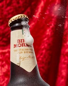 a close up of a bottle of beer on a red background