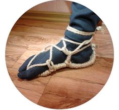 a person's feet in blue shoes with rope tied around them on a wooden floor