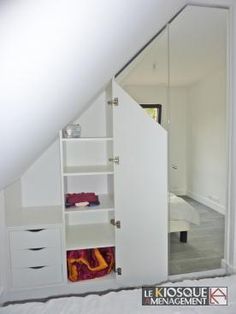 an open closet in the corner of a room with white walls and drawers on it