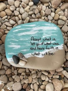 a rock with a quote on it sitting in some rocks and gravel that says, accept what is let go of that was, and have faith in what will be