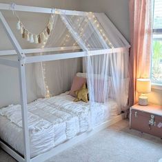 a pink and white bedroom with a canopy bed in the corner, rugs on the floor