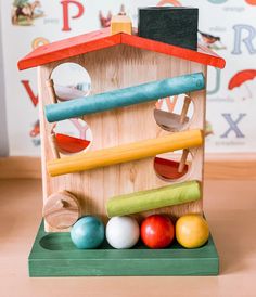 a wooden toy house with balls and sticks