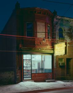 an old building is lit up at night with neon lights on the front and side windows