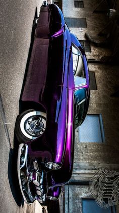 a purple motorcycle parked on the side of a road next to a building with windows