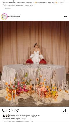 a woman sitting on top of a table surrounded by candles and flowers in vases