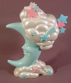 a ceramic figurine of a crescent moon with stars on it's head