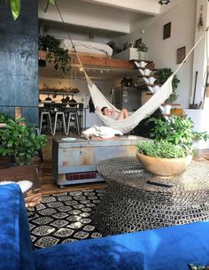 a man laying in a hammock on top of a couch next to a table