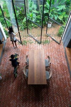 an overhead view of a table and chairs in a room with glass walls that look out onto the jungle