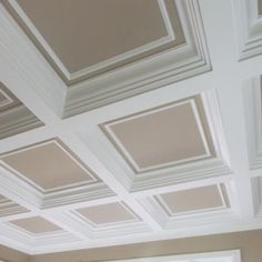 a living room filled with lots of white furniture and ceiling tiles on top of it