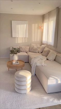 a living room filled with lots of white furniture and pillows on top of the couch