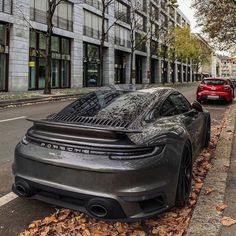 a black sports car parked on the side of a road next to a red car